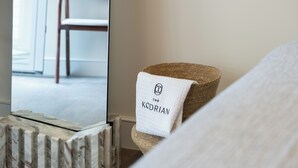 Hotellihuone, jossa on sänky, puinen tuoli ja peili, johon heijastuu tuoli ja ikkuna.