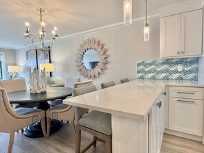 A modern kitchen with a central island, white cabinetry, and a decorative mirror. - Harbour Light Towers 1702 Beachfront and Renovated (Clearwater Beach)