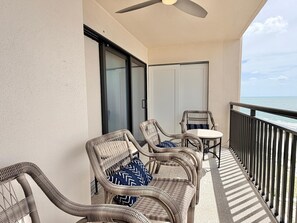Ein Balkon mit Korbmöbeln, einem Deckenventilator und Blick aufs Meer.