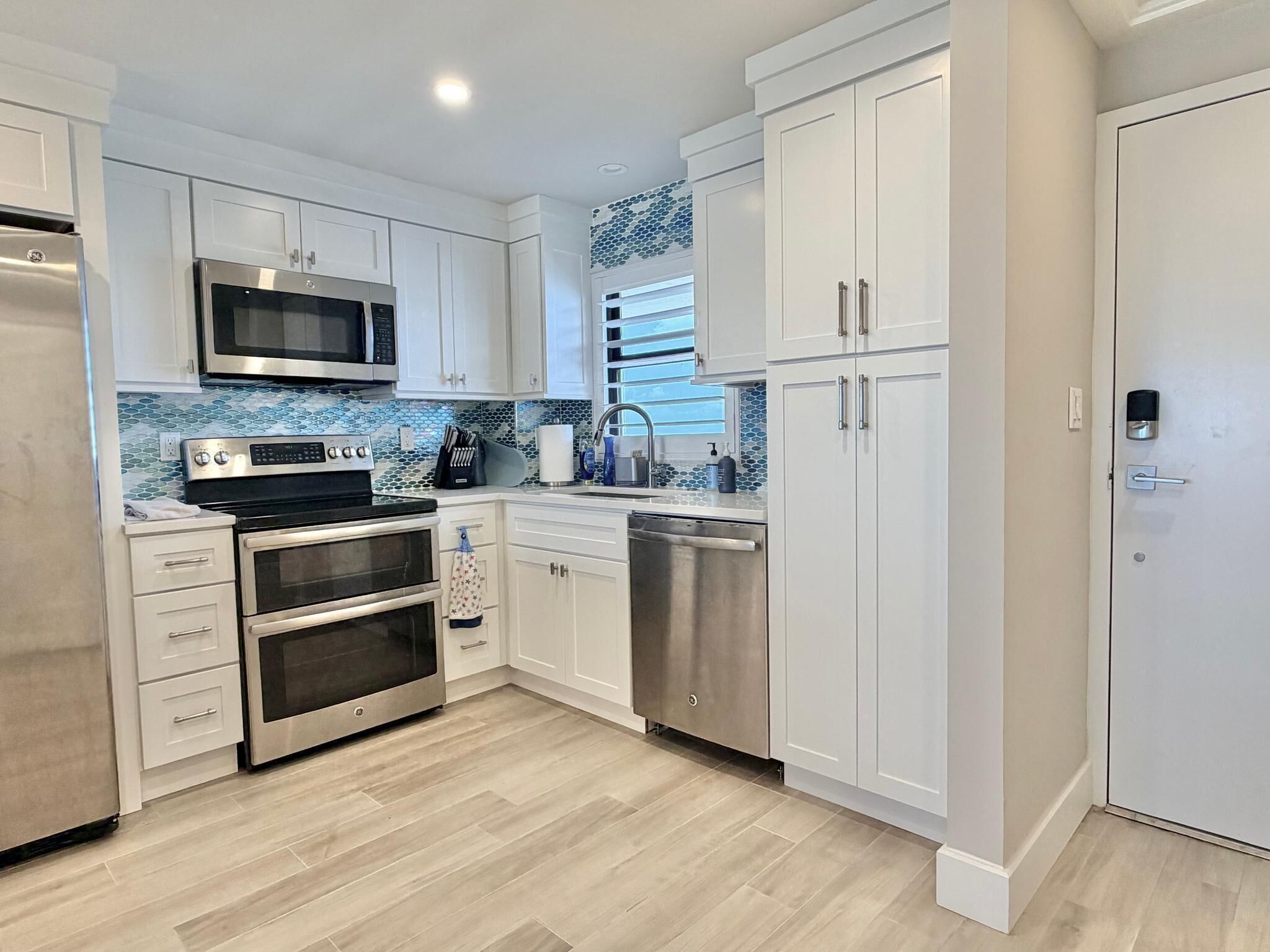 A modern kitchen with white cabinetry, a stainless steel oven, a microwave, and a dishwasher.