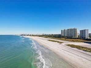 A beach with a clear sky, a sandy shore, and high-rise buildings in the background. - Harbour Light Towers 1702 Beachfront and Renovated (Clearwater Beach)