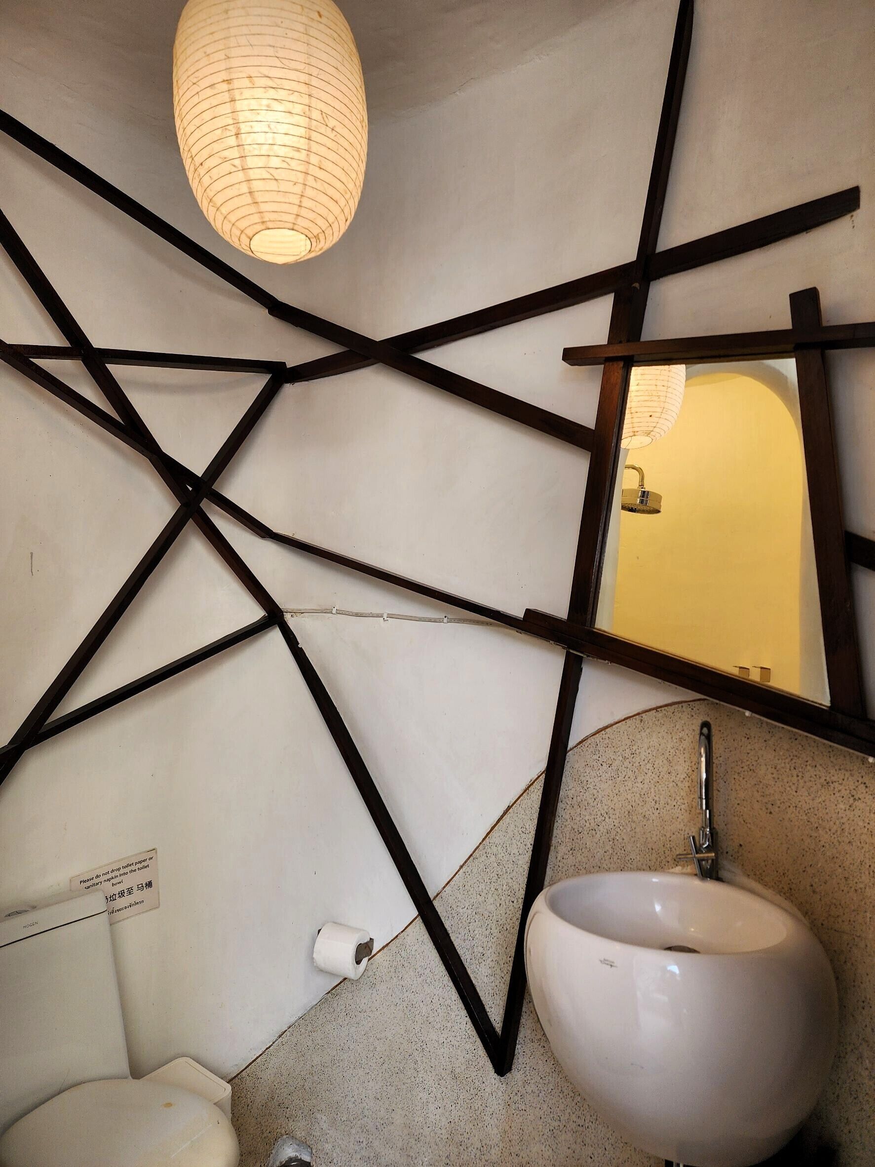 A bathroom with a white sink, a mirror, and a hanging light fixture.
