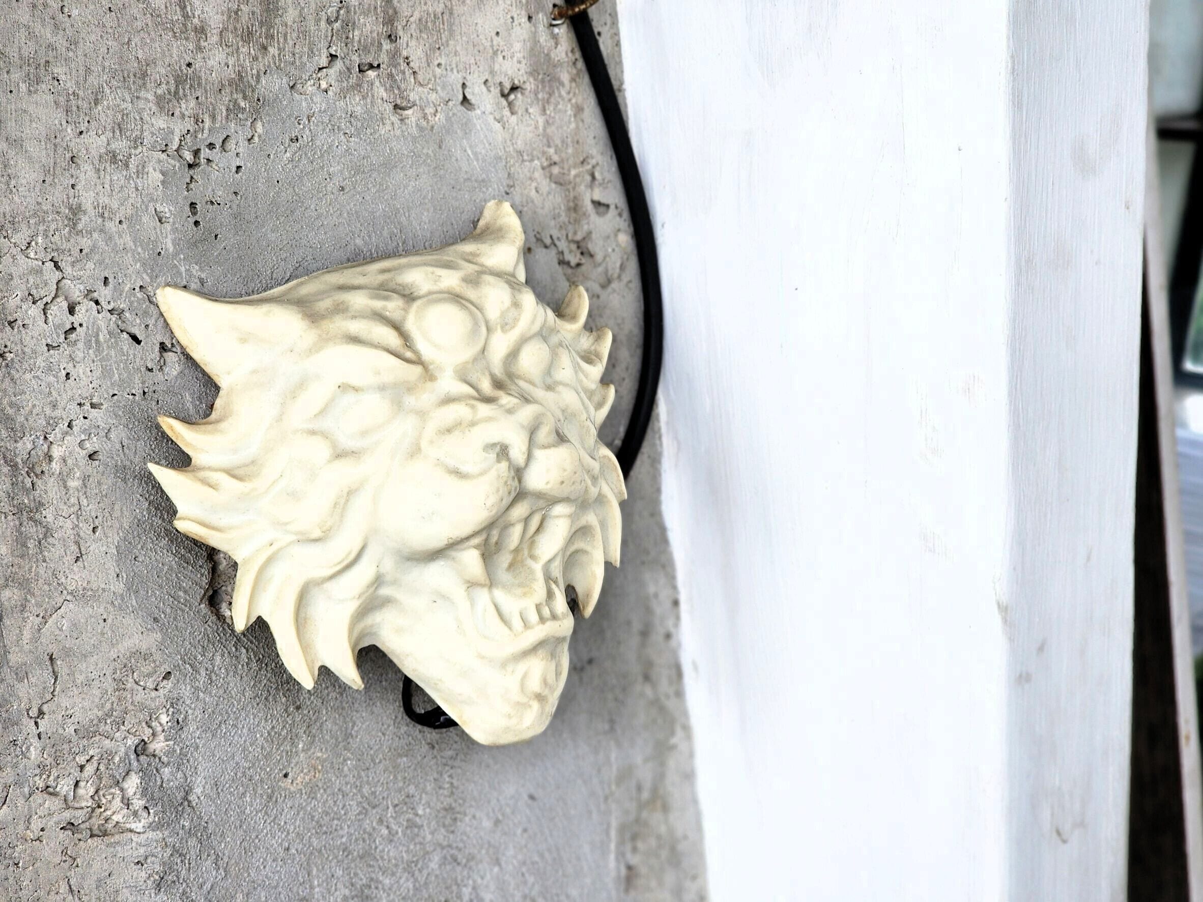 Un mur à la texture particulière orné d’un bas-relief représentant la tête d’un lion sculptée.