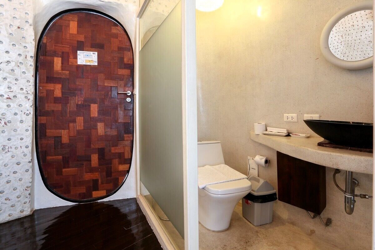A bathroom with a wooden door, a toilet, a sink, and a mirror.