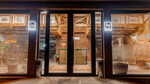 A building entrance with a brick facade, large glass doors, and a sign with the number 030.