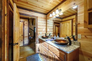 Een houten interieur van een chalet, met een keukenhoek, een groot eiland, een spoelbak, een kookplaat en een spiegel boven het aanrecht.