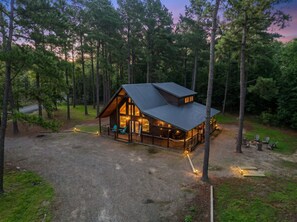 Een chalet met een veranda, grote ramen en een vuurplaats.