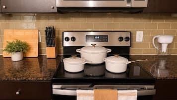A kitchen with a stove, pots, a microwave, and a potted plant.