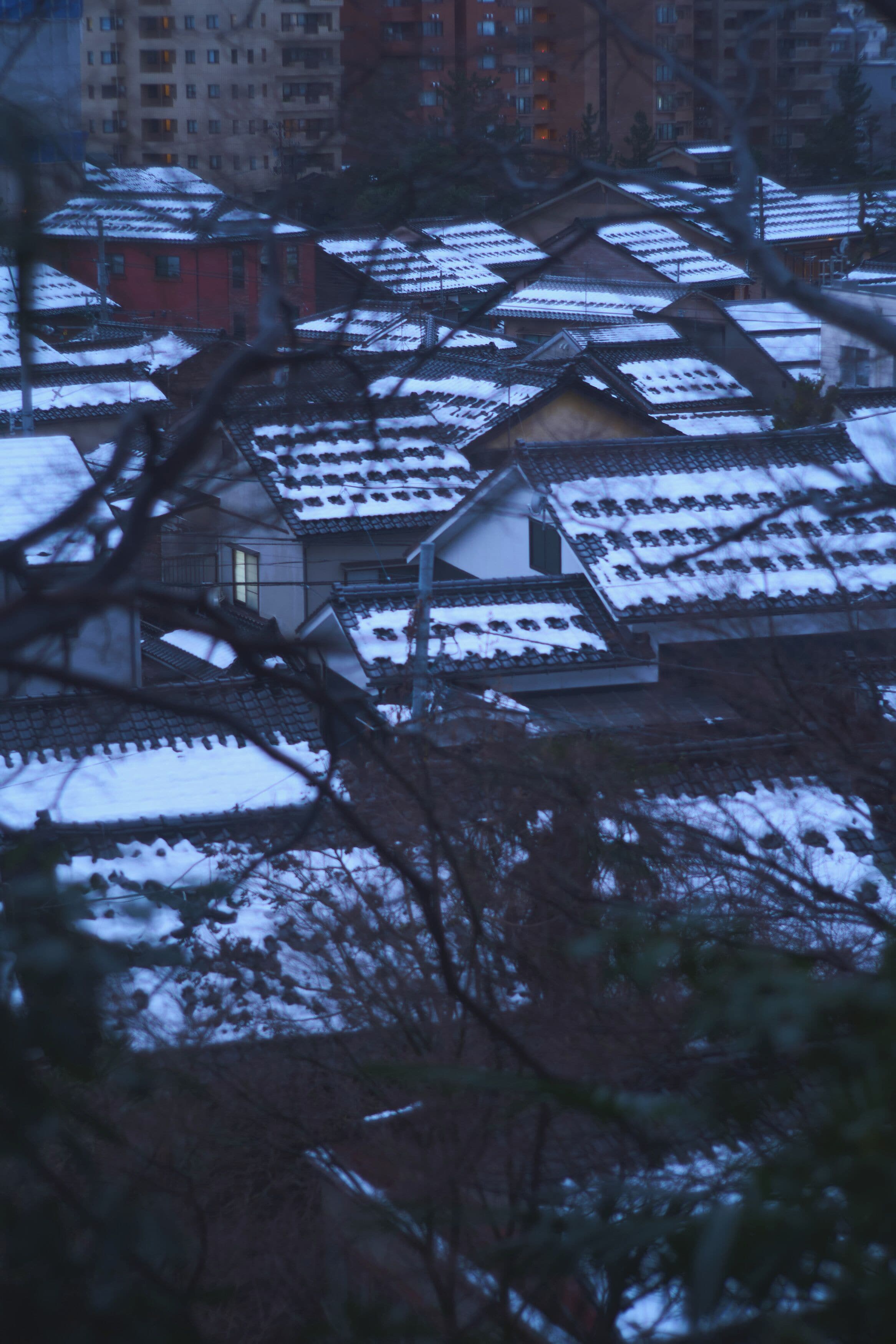 A residential area with traditional buildings covered in snow, featuring a mix of modern and older architecture.
