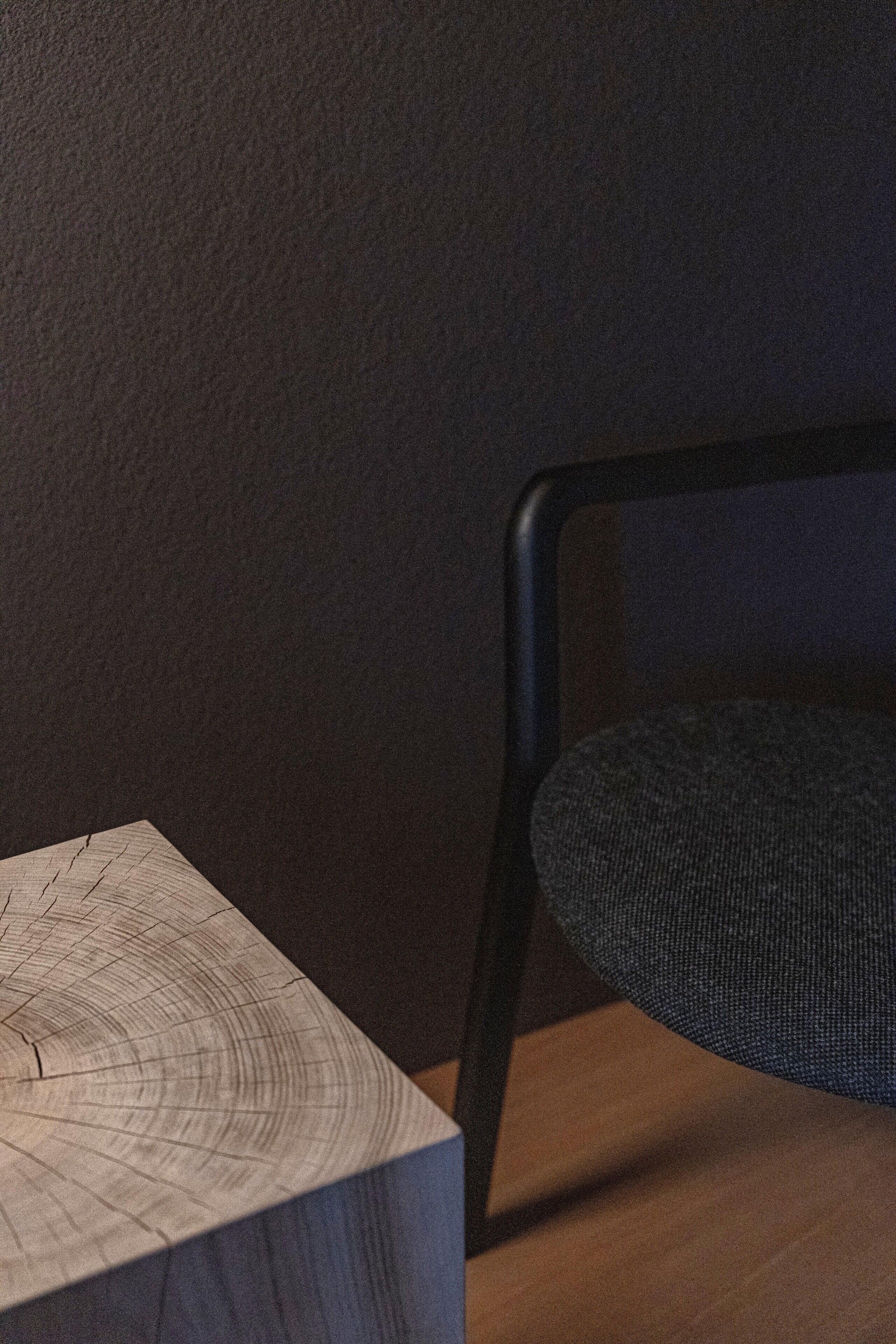 Une table en bois ornée d’un motif circulaire et une chaise noire avec un siège en osier tressé.