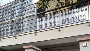 Un immeuble résidentiel doté d’une entrée sécurisée par un portail, d’une boîte aux lettres bien visible et du numéro « 21 » peint sur le mur.