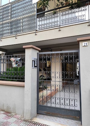 A residential building with a gated entrance, a visible mailbox, and a number '21' on the wall.
