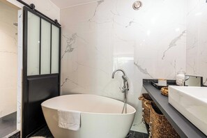 A modern bathroom with a freestanding bathtub, a vanity with a mirror, and a shower area.