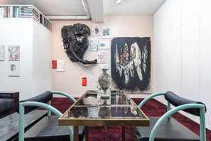 Eine Kunstgalerie mit einem Glastisch, Stühlen und verschiedenen Kunstwerken an den Wänden.