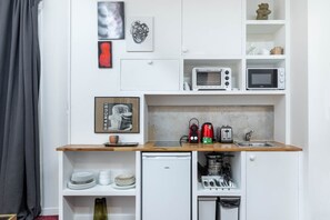 Eine kleine Küchenzeile mit Mikrowelle, Toaster, Wasserkocher und einem kleinen Kühlschrank.