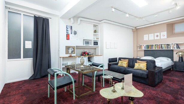 Una habitació d'hotel moderna amb un llit, un sofà, una taula de dinar i una cuineta.