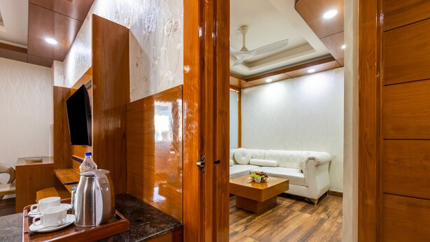 A modern interior with a wooden counter, a white sofa, and a ceiling fan. - Hotel Golden Place 377 (Gurugram)