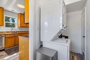Eine kleine Küche mit Holzschränken, einem weißen Kühlschrank und einer Mülleimer.