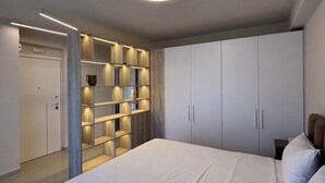 Een slaapkamer met een groot bed, inbouwplanken en een plafondlamp.