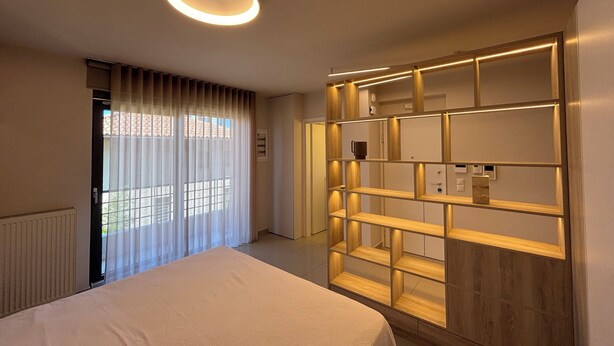 Een hotelkamer met een bed, een ingebouwde boekenkast en een plafondlamp.