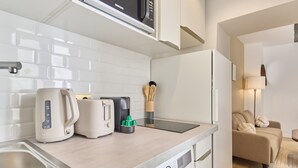 Eine kleine Küchenzeile mit Mikrowelle, Wasserkocher, Toaster und Kaffeemaschine.