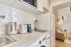 Eine kleine Küchenzeile mit Mikrowelle, Wasserkocher, Toaster und Kaffeemaschine.