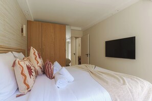 Ein Hotelzimmer mit Bett, Kissen, Fernseher und Kleiderschrank.