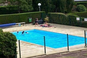 Ein Schwimmbecken mit einem Sicherheitsnetz, umgeben von einem angelegten Garten.