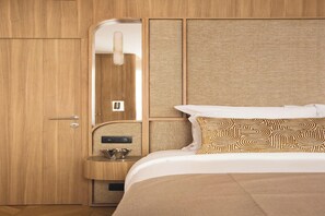 A hotel room with a wooden wardrobe, a built-in vanity with a mirror, and a bed with patterned pillows. - Sublime Suite Saint Honoré, Elysée Palace (Paris)