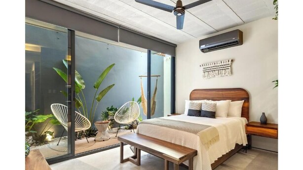 Ein modernes Schlafzimmer mit einem großen Bett, einer Bank und einem Deckenventilator.