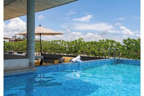 A swimming pool with a tiled edge, lounge chairs, and umbrellas. - Ocean Boutique Condos (Playa del Carmen)