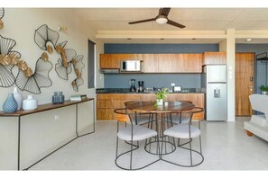 A modern kitchen with wooden cabinets, a microwave, and a refrigerator. - Ocean Boutique Condos (Playa del Carmen)