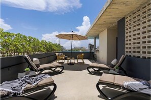 A rooftop lounge with lounge chairs, a table, and an umbrella. - Ocean Boutique Condos (Playa del Carmen)