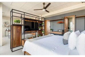 A modern bedroom with a bed, a TV, a desk, and a wardrobe. - Ocean Boutique Condos (Playa del Carmen)