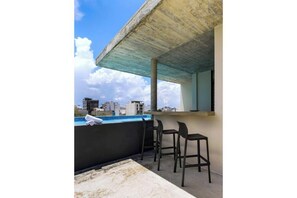 A rooftop terrace with a concrete ceiling, a pool, and two black bar stools. - Ocean Boutique Condos (Playa del Carmen)