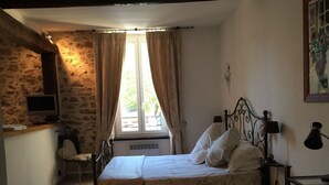Een slaapkamer met een bed, een stoel, een bureau en een raam met gordijnen.