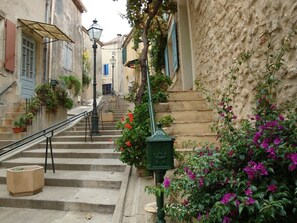 A narrow street with steps leading to a building, a street lamp, and potted plants. - A romantic getaway on the square in Saint-Chinian, featuring fantastic hiking and wine (saint-chinian)