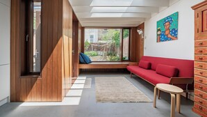 Ein modernes Interieur mit Holzboden, einem roten Sofa, einem kleinen Tisch und einem Holzschrank.
