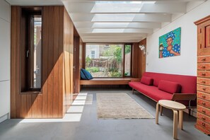 Ein modernes Interieur mit Holzboden, einem roten Sofa, einem kleinen Tisch und einem Holzschrank.