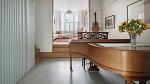 Ein Zimmer mit einem Klavier, einer Gitarre und einer Vase mit Sonnenblumen.