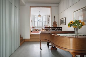 Ein Zimmer mit einem Klavier, einer Gitarre und einer Vase mit Sonnenblumen.