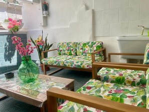 A room with a cactus-patterned sofa, a green vase with pink flowers, and a tiled wall. - A small house 5 minutes from the beach, with a beautiful terrace, in the city center (Monopoli)