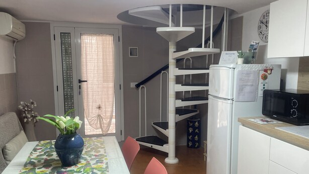 Una cocina con un refrigerador blanco, un microondas y un comedor con una mesa cubierta por un mantel estampado con motivos de cactus.