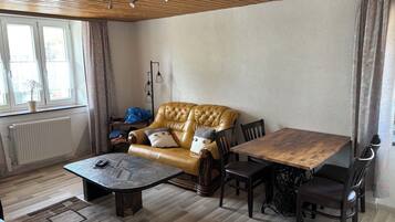 Ein Wohnzimmer mit einem Ledersofa, einem Holztisch und einem Esstisch mit Stühlen.