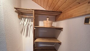 Een houten trap die leidt naar een bergzolder met planken en een hangrek.