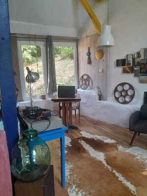 A room with a laptop on a wooden table, a cowhide rug, and a hanging light fixture.