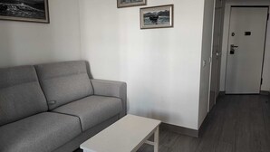 A living room with a grey sofa, a white coffee table, and two framed pictures on the wall. - Rocha's Corner (Portimão)