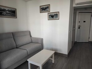 A living room with a grey sofa, a white coffee table, and two framed pictures on the wall. - Rocha's Corner (Portimão)