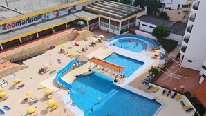 A rooftop swimming pool area with multiple pools, sun loungers, and a children's play area. - Rocha's Corner (Portimão)