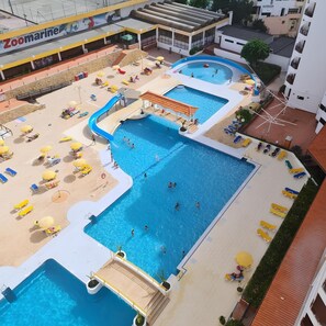 A rooftop swimming pool area with multiple pools, sun loungers, and a children's play area. - Rocha's Corner (Portimão)